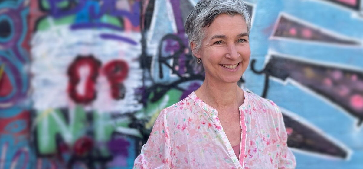 Vivian Glas - zertifizierte LRS Deutschland Trainer steht vor einer Wand einem blauen Graffitibild